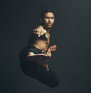 Full length shot of a handsome young man performing a martial arts kick in the studio