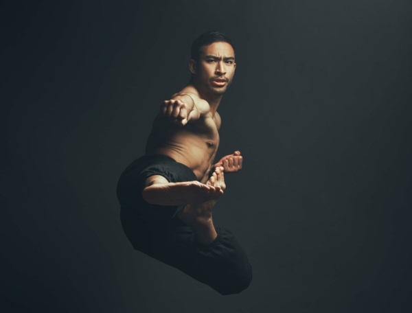 Full length shot of a handsome young man performing a martial arts kick in the studio