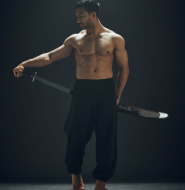 Full length shot of a handsome young man standing alone in the studio and posing with a broadsword