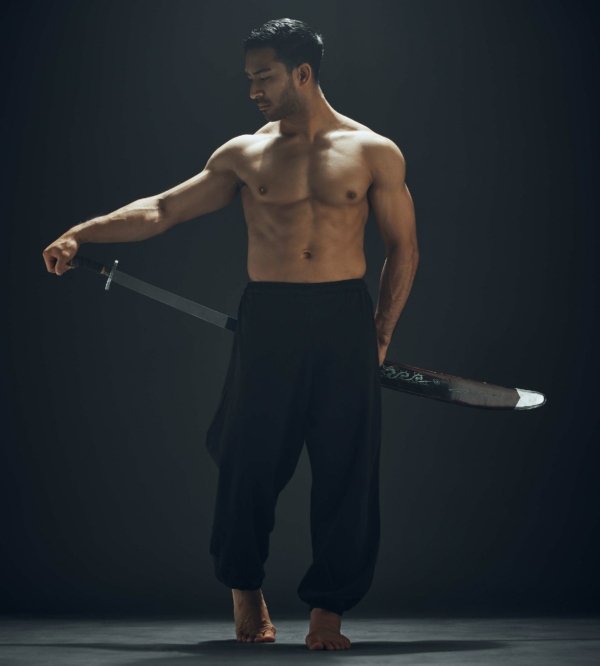 Full length shot of a handsome young man standing alone in the studio and posing with a broadsword