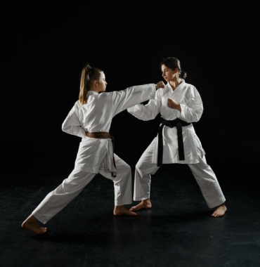Two female karatekas in kimono, strike in action