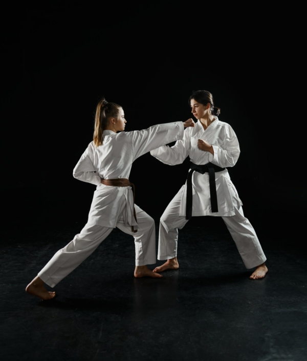 Two female karatekas in kimono, strike in action